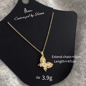 Detailed view of a gold butterfly pendant necklace with white zircons on a jewelry card