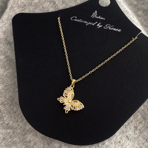 Detailed close-up of a gold-plated butterfly pendant set with sparkling white zircons