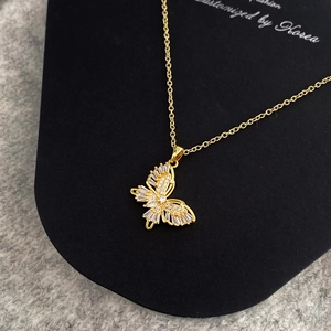 Close-up of gold butterfly pendant with baguette-cut zircons on a delicate O-chain necklace