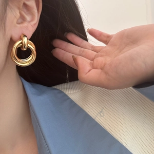 Minimalist interlocking triple circle gold hoop earrings on female model