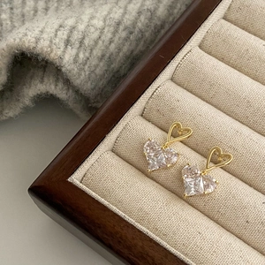 Detail of heart-shaped gold-plated earrings with clear cubic zirconia in a jewelry box
