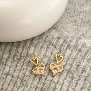 Close-up of gold-plated heart earrings with sparkling cubic zirconia on grey knit background