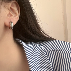 Elegant silver metal hoop earrings with quilted pattern on a fashion model