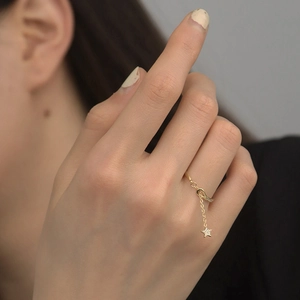 Detail of adjustable gold-plated star charm ring with zircon stones on finger