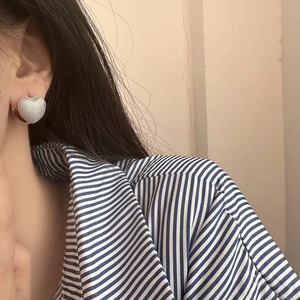Close-up of silver heart-shaped earring with fine textured finish on a model