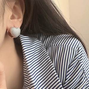 Elegant heart-shaped hoop earrings with a textured silver-tone finish on a female model