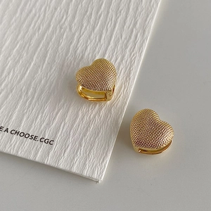 Detailed macro view of golden heart-shaped hoop earrings with textured beaded finish
