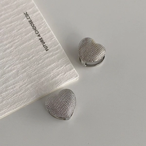 Close-up of heart-shaped hoop earrings with a textured grainy silver plated finish