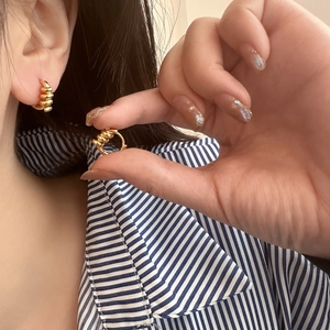 Détail des boucles d'oreilles huggies dorées torsadées avec un design spirale