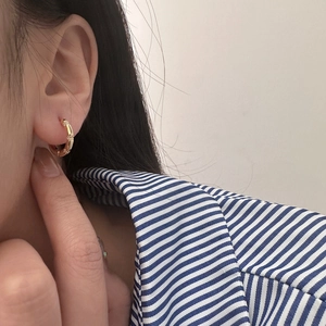 Close-up of gold hoop earrings with micro-inlaid stones on a model's ear