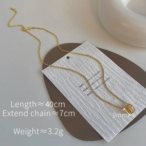 Detail of a gold-plated cylinder pendant necklace with sparkling cubic zirconia pavé