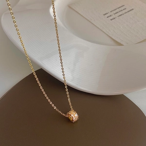 Elegant gold-plated cylinder necklace with sparkling pavé zircons on a white plate