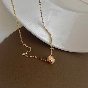 Macro detail of a gold-plated cylinder pendant with shimmering pavé zircon stones
