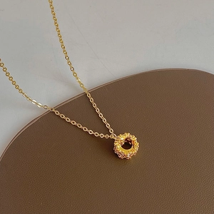 Close-up of gold-plated lucky wheel necklace with zircon on a leather surface
