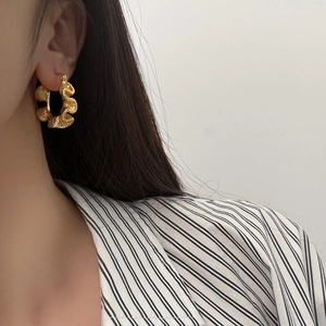 Artistic gold-plated wave hoop earrings with textured ruffles shown on a female model