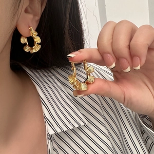 Detailed close-up of gold-plated ruffled hoop earrings with artistic wavy texture