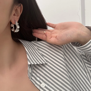 Detail view of silver pleated ripple hoop earrings with elegant textured wave design