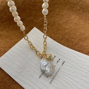 Detail of baroque pearl and gold heart pendant on a mixed metal link and pearl necklace