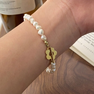 Dettaglio del bracciale di perle barocche con chiusura floreale dorata sul polso