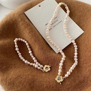 Dettaglio collana e bracciale di perle barocche con chiusura a fiore dorata