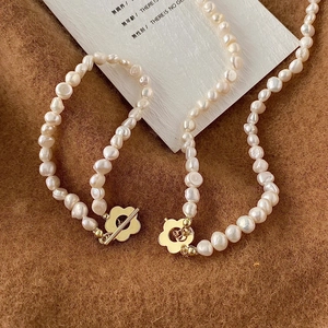 Dettaglio della collana di perle barocche con chiusura a fiore dorata su velluto