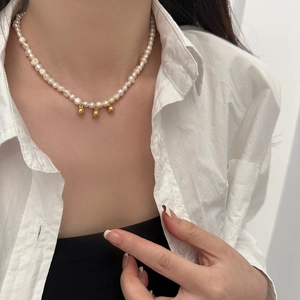 Détail du collier de perles d'eau douce avec trois pendentifs boules dorées sur mannequin