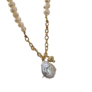 Baroque pearl necklace with heart pendant and gold chain on white background