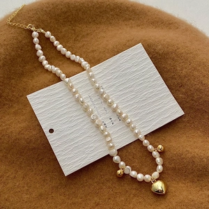 Détail du collier de perles d'eau douce avec pendentif cœur doré et fermoir ajustable