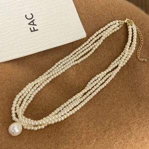 Three-layer faux pearl necklace with a large teardrop pearl pendant and gold clasp