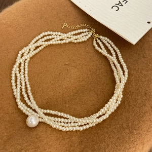 Close-up of a multi-layer rice pearl necklace with a large teardrop pearl pendant and gold clasp
