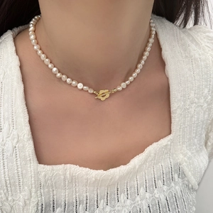 Elegante collana di perle naturali con chiusura a fiore dorato su modella in pizzo