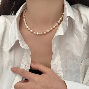 Detailed view of French baroque necklace with irregular pearls and golden beads on model