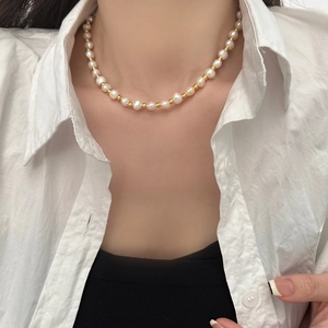 Close-up of French baroque freshwater pearl necklace worn by a model on white shirt