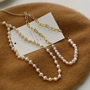 Detailed macro view of baroque freshwater pearl necklace with golden chain on wool beret