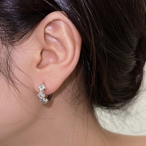 Macro detail of silver floral hoop earrings with sparkling cubic zirconia on a model ear