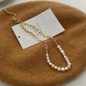 Close-up of asymmetric necklace with gold paperclip chain and natural freshwater pearls