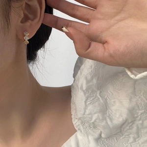 Detailed view of four-leaf clover gold hoop earrings set with sparkling zircon stones