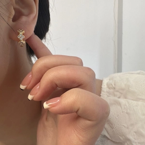 Detailed view of gold clover earrings with sparkling zircon inlay worn by a model