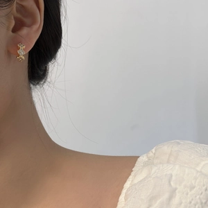 Macro detail of triple gold flower earrings with white zircons on a model