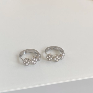 Detailed close-up of silver hoop earrings with triple clover-shaped cubic zirconia clusters