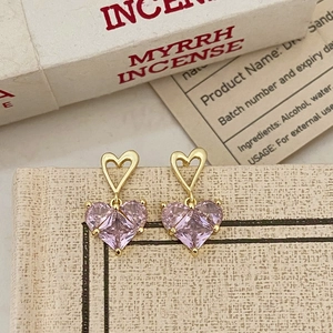 Gros plan de boucles d'oreilles cœur rose avec détails dorés ajourés élégants