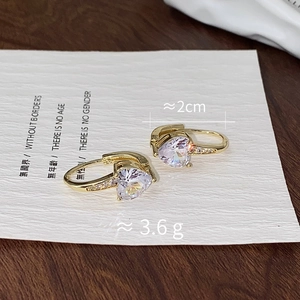 Detail of heart-shaped zircon earrings with gold plating and fine diamond accents
