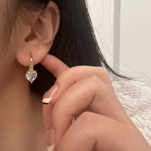 Elegant gold heart cubic zirconia drop earrings for women worn on ear in soft light