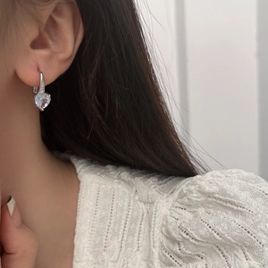 Macro shot of sparkling heart-shaped zircon earrings with silver crystal studded clips