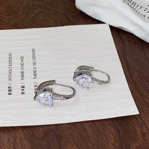 Detailed macro view of heart-shaped zircon earrings with silver plating on display card