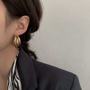 Fashion gold layered hoop earrings with chunky metallic texture worn by a model