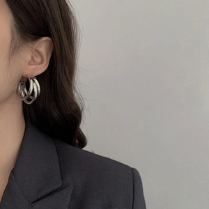 Close-up of triple-layered silver hoop earrings with a polished metallic finish on model