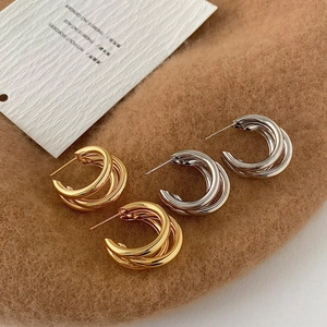 Modern triple-intertwined hoop earrings in polished gold and silver finishes