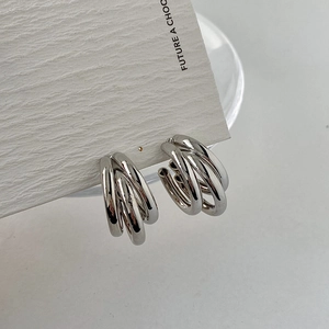 Detailed macro view of triple-layered interwoven silver metal hoop earrings on card