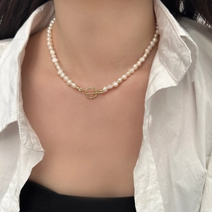 Close-up of irregular freshwater pearl necklace with gold toggle clasp on a neck